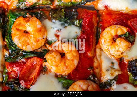 Pizza con gamberi, pomodori e spinaci, primo piano. Sfondo pizza mediterranea. Foto di alta qualità Foto Stock