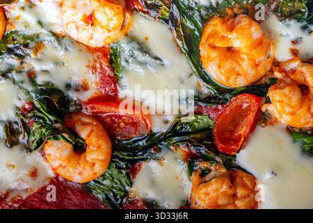 Pizza con gamberi, pomodori e spinaci, primo piano. Sfondo pizza mediterranea. Foto di alta qualità Foto Stock