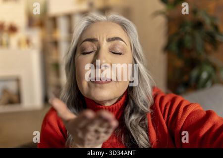 Bacio aereo. Bella donna anziana dai capelli lunghi che manda un bacio aereo Foto Stock