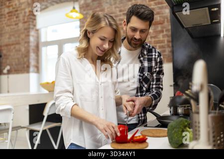 Amata giovane coppia che taglia verdure al bancone del cucinino, uomo e donna innamorati cucinare cibo insieme a casa Foto Stock