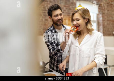 Amata giovane coppia che taglia verdure al bancone del cucinino, uomo e donna innamorati cucinare cibo insieme a casa Foto Stock