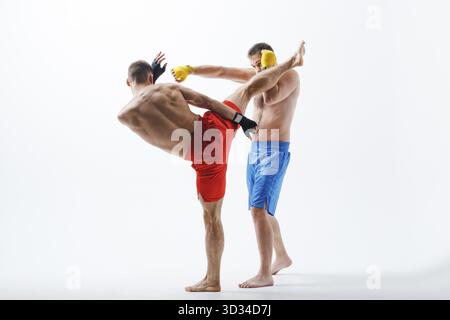 Due uomini boxer lotta muay thai boxing sfondo bianco Foto Stock