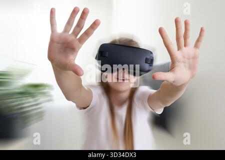 Ragazza che indossa occhiali VR gioco, che si muove in realtà virtuale Foto Stock
