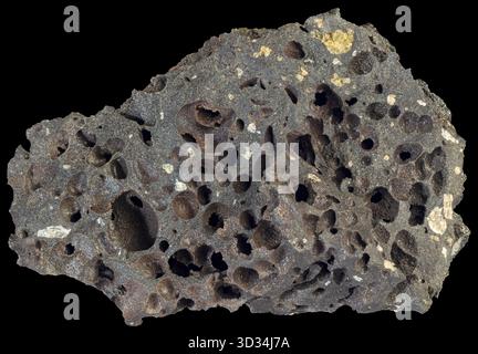 Basalto vescicolare scuro proveniente dall'Islanda, caratterizzato da abbondanti vescicole arrotondate create dalla fuga di gas vulcanici durante l'eruzione. Foto Stock