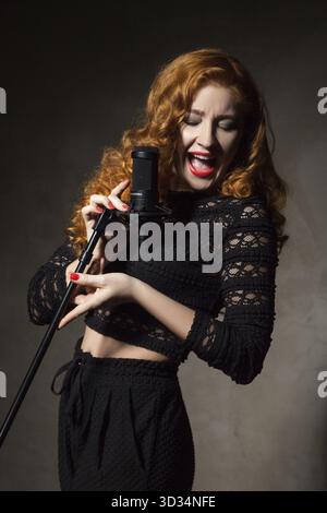Ritratto di i capelli rossi donna firma in mic con ampia bocca aperta Foto Stock