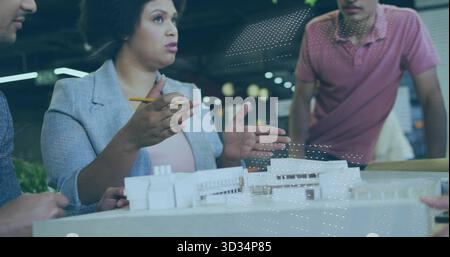 Presentando una donna architetto che indossa un blazer, gestendo con una matita al modello in studio, con i colleghi Foto Stock