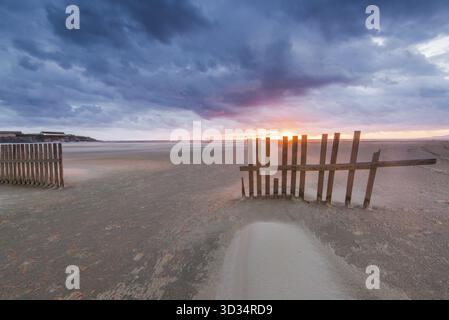 Il vento soffia la sabbia sulla spiaggia di Tarifa in Spagna al tramonto Foto Stock
