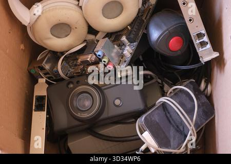 Vecchi accessori elettronici tecnologici imbottiti in una scatola. Foto Stock