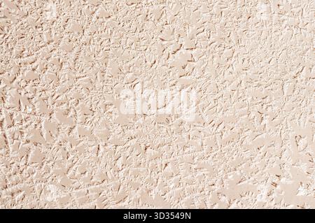 Primo piano di una parete decorativa in stucco con finitura grossolana, che presenta un motivo irregolare e organico sulla superficie Foto Stock