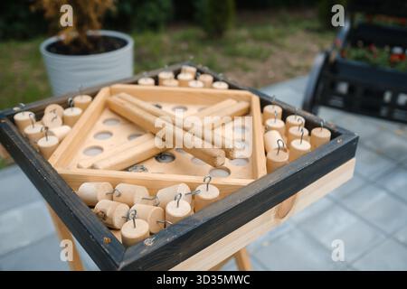 Un tavolo da gioco in legno è allestito all'aperto in un cortile. Il tabellone presenta fori per i pezzi di gioco e vari pezzi di legno sono disposti in modo ordinato, in attesa Foto Stock