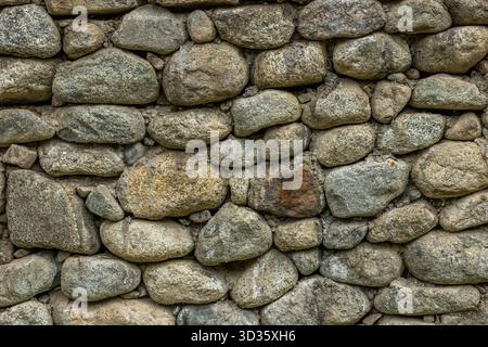 Rustico muro di pietra fatto di varie pietre in ambiente rurale Foto Stock