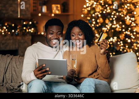 Allegra coppia giovane ama fare shopping online di Natale mentre è accogliente a casa Foto Stock