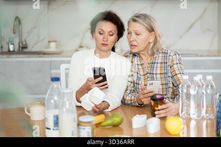 Due donne che scansionano prodotti diversi utilizzando il proprio smartphone Foto Stock