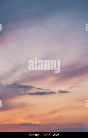 Un tranquillo cielo serale dipinto in tonalità pastello di rosa, arancione e viola. Le morbide nuvole si allungano all'orizzonte, creando un atmo tranquillo e sognante Foto Stock
