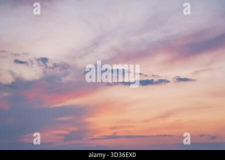 Un tranquillo cielo serale dipinto in tonalità pastello di rosa, arancione e viola. Le morbide nuvole si allungano all'orizzonte, creando un atmo tranquillo e sognante Foto Stock