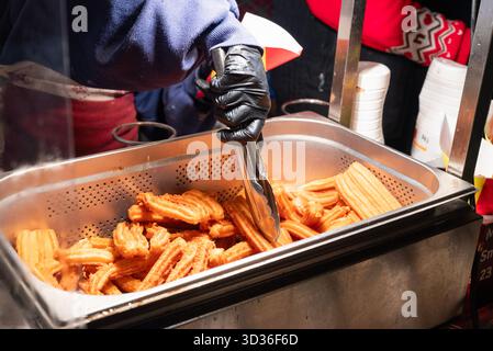 Preparare churros fritti di cibo di strada nel centro della città al mercatino di Natale di Cracovia, Polonia. Foto Stock