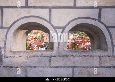 Vista panoramica della città vecchia di Český Krumlov con la torre della chiesa di San Vito attraverso un paio di finestre del castello. Foto Stock
