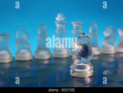Cavallo opposto che affronta una fila di pezzi di scacchi su una scacchiera, simboleggiando strategia, leadership e pensiero chiaro negli affari o nel processo decisionale Foto Stock
