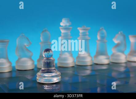 Pedone di fronte a una fila di pezzi di scacchi su una scacchiera, simboleggiando strategia, leadership e un chiaro pensiero in ambito commerciale o decisionale Foto Stock