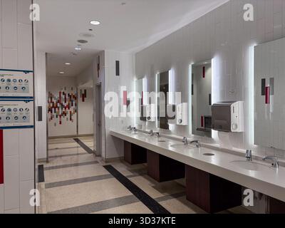 Moderno bagno interno all'Aeroporto Internazionale Pearson di Toronto. Dispone di lavandini multipli, specchi illuminati, asciugatrici per le mani e pareti piastrellate con COVID-1 Foto Stock