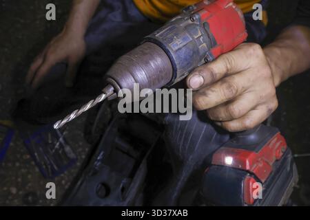 Primo piano del trapano a batteria che tiene la mano dell'operatore. falegname con utensile elettrico pronto per la riparazione, la costruzione e la manodopera nell'industria, con messa a fuoco Foto Stock