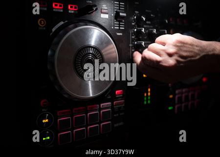 DJ che mixa brani con controller elettronico di musica. Primo piano del mixer sonoro giradischi DJ nel nightclub. Produttore musicale DJ rhythm and sound. Mix audio Foto Stock