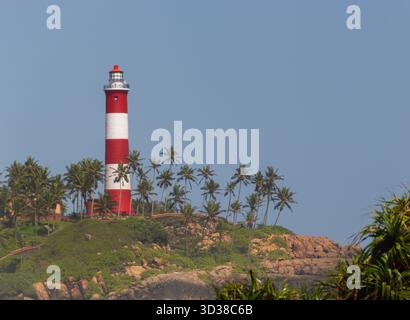 Faro a righe rosse e bianche in piedi su un promontorio tropicale Foto Stock