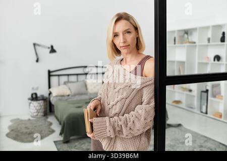 Una donna bionda si rilassa in abiti comodi, circondati da un arredamento accogliente ed elegante. Foto Stock