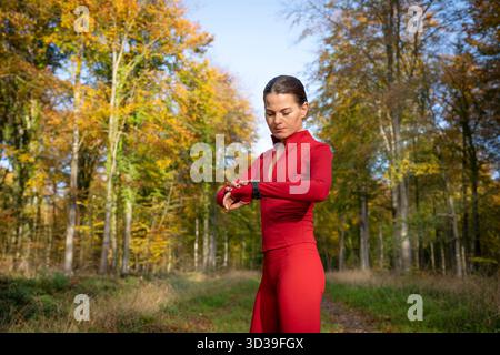 indossa una runner sportiva che controlla il suo fitness tracker all'aperto nel parco Foto Stock