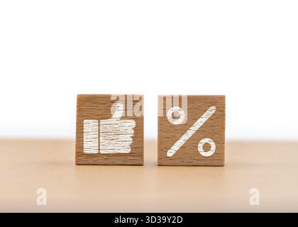 Su una superficie liscia si trovano due blocchi di legno, uno con il simbolo del pollice verso l'alto e l'altro con il simbolo della percentuale. Questo accordo sottolinea Foto Stock