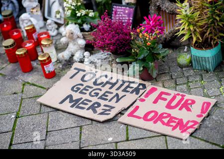 Oldenburg, Germania. 5 novembre 2025. Sulla scena del crimine nel centro della città si trovano due cartelli che recano "Figlie contro Merz" e "per Lorenz", oltre a numerosi fiori, candele e foto, in memoria di Lorenz, ferita a morte da un colpo di pistola della polizia. Dopo la sparatoria mortale di Lorenz ventunenne a Oldenburg, l'ufficio del pubblico ministero ha accusato un agente di polizia per omicidio negligente. Crediti: Hauke-Christian Dittrich/dpa/Alamy Live News Foto Stock