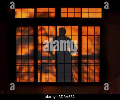 Ombre di un uomo in kimono, sul balcone dietro porte scorrevoli shoji in una casa tradizionale giapponese, Yamanouchi, Nagano, Giappone Foto Stock