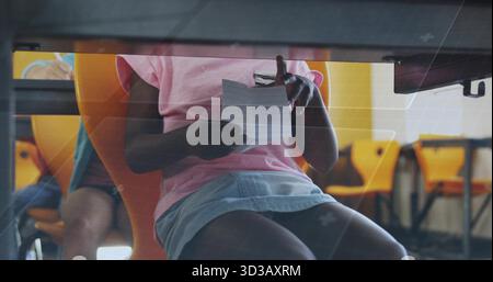 Ragazza che legge indossa una camicia e una gonna rosa in classe, con matita di carta sedie gialle gambe da scrivania Foto Stock