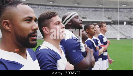 Giocatori di rugby in piedi che mettono la mano sul petto sul campo indossando maglie, pantaloncini corti e fascia a goalpost Foto Stock