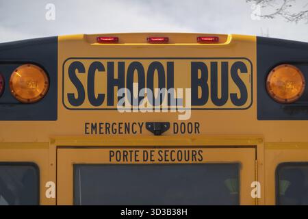 Calgary, Alberta, Canada. 14 aprile 2025. Un primo piano di uno scuolabus giallo mette in evidenza la porta di emergenza posteriore e le luci di emergenza, garantendo la sicurezza degli studenti Foto Stock