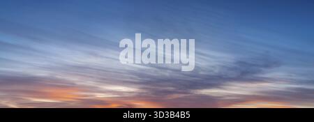 Un grande panorama del cielo prima del tramonto, basse nuvole a strisce di colore rosso brillante Foto Stock
