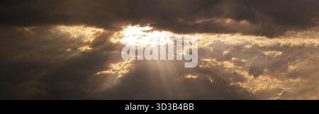 Un'atmosfera mistica è creata dal tempo in questa foto panoramica, che mostra un cielo drammatico con raggi del sole che penetrano attraverso le aperture nel d Foto Stock