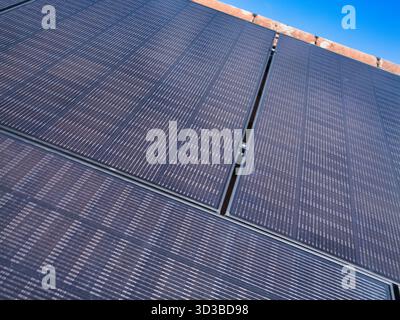 Primo piano di pannelli fotovoltaici sul tetto di una casa contro un cielo blu brillante nel Regno Unito, a simboleggiare l'energia pulita e l'efficienza domestica moderna. Foto Stock
