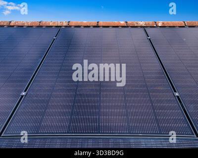 Primo piano di pannelli solari residenziali sul tetto di una casa sotto un cielo blu chiaro nel Regno Unito, catturando energia pulita e l'efficienza della casa moderna. Foto Stock