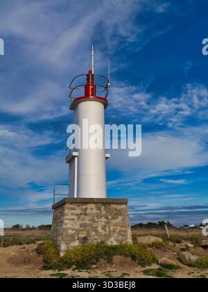 56270 Ploemeur, Francia - settembre 28 2025: Faro del porto a Kerroch Port, Ploemeur, Bretagna, Francia, si innalza contro un cielo azzurro vivido, catturato dalla nitida luce del tardo pomeriggio. Foto Stock
