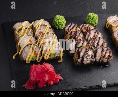 Cibo, set di sushi al forno con wasabi e zenzero su nero Foto Stock