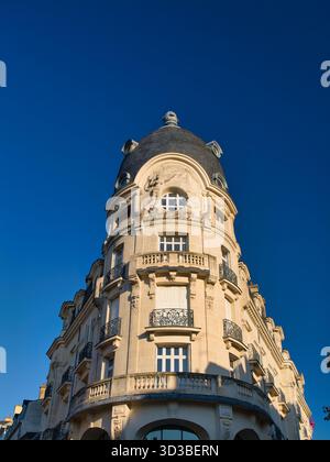Vannes, Francia - settembre 30 2025: Cupola d'angolo ornata e facciata in pietra dell'edificio Au Progres a Vannes, Francia, illuminata dal sole del mattino contro un cielo blu profondo. Foto Stock