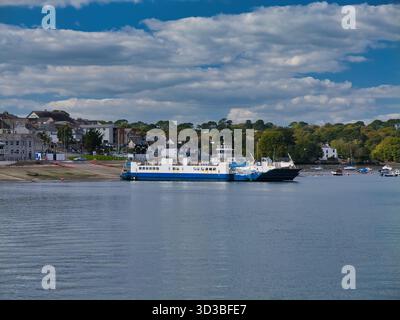 Plymouth, UK  - Sep 25 2025: Devonport to Torpoint chain ferry at the slip on the River Tamar in Plymouth, UK, under bright clouds, with small boats and hillside homes along the wooded shore. Foto Stock