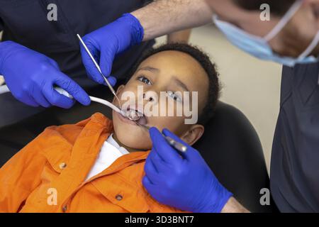 In odontoiatria. Il dentista e il suo assistente curano i denti dei ragazzi Foto Stock