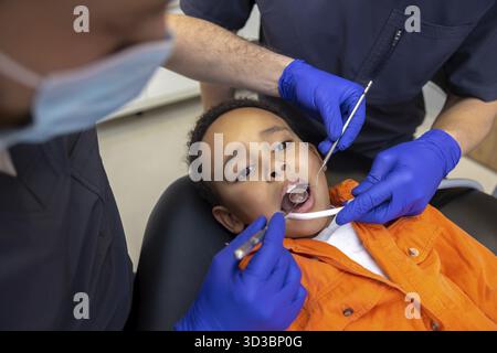 In odontoiatria. Il dentista e il suo assistente curano i denti dei ragazzi Foto Stock