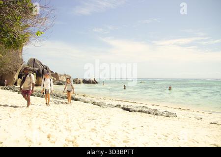 Turisti che camminano lungo Anse Source d'Argent Beach, Seychelles Foto Stock