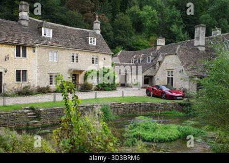 Castle Combe, Regno Unito - 17 settembre 2025 incantevoli cottage in Water Lane, Castle Combe, Cotswolds con un rosso Lotus Emira parcheggiato. Il piccolo Foto Stock