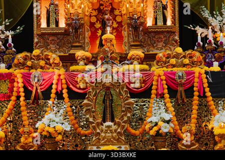 Dettagliata offerta tradizionale messicana del giorno dei morti con fiori di calendula, candele e figure religiose, che celebrano la vita dopo la morte. Foto Stock