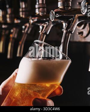 Cibo, primo piano del barman mano alla spillatura della birra che versa una birra lager alla spina Foto Stock