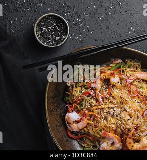Cibo, mescolare gli spaghetti con verdure e gamberetti nel recipiente nero Foto Stock